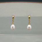 Vue de face de boucles d'oreilles goutte baroque ovale or sur présentoir